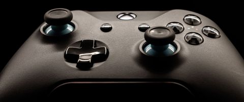 A black game controller lit against a dark background
