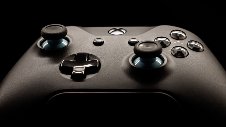 A black game controller lit against a dark background