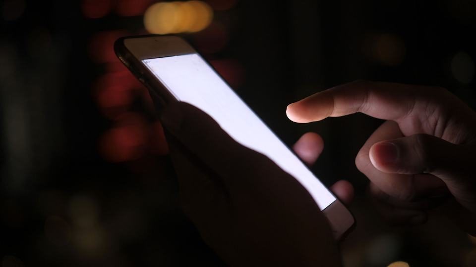 A phone lit up in a hand at night