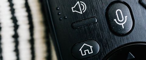 A remote control with home and voice buttons, close up