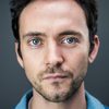 George Blagden as Fr. Carey (segment: Blight)